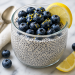 Blueberry lemon chia pudding topped with fresh blueberries, lemon zest, and a lemon slice in a glass bowl.